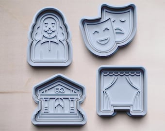May include: Four light blue cookie cutters. The shapes include a bust of a man, comedy and tragedy masks, a building with columns, and a stage with curtains. These are likely for baking themed cookies.