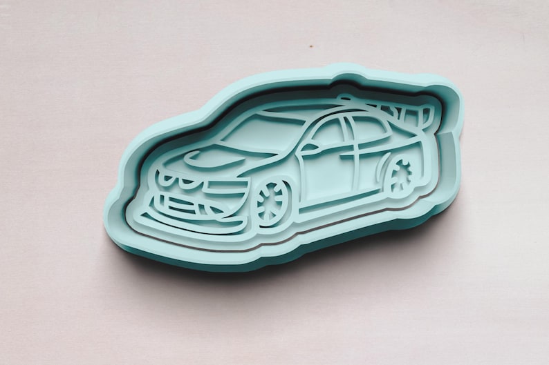 May include: A light blue plastic cookie cutter shaped like a race car. The car has a black outline and a detailed design.
