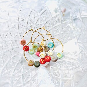May include: Set of six gold-toned wine glass charms with colorful beads and gold lettering spelling out "CARE" and "ZIP".