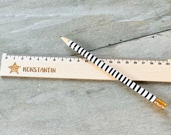 May include: A wooden ruler with a black and white striped pencil. The ruler is marked with numbers from 0 to 20 and has the name "KONSTANTIN" engraved on it. A gold star is also engraved on the ruler.