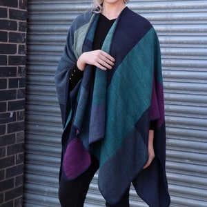 model wearing the poncho as an outer layer over a jumper