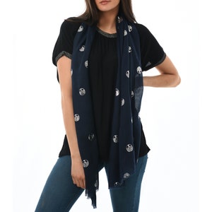 model wearing a navy blue lightweight scarf around the neck, the scarf has an all over silver foil tree of life pattern,