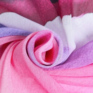 Pu&ograve; includere: Primo piano di un tessuto morbido, sfumato di rosa, viola e bianco. Il tessuto &egrave; piegato e drappeggiato, creando un motivo a spirale.