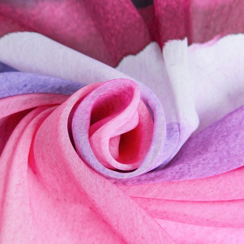 Pu&ograve; includere: Primo piano di un tessuto morbido, sfumato di rosa, viola e bianco. Il tessuto &egrave; piegato e drappeggiato, creando un motivo a spirale.