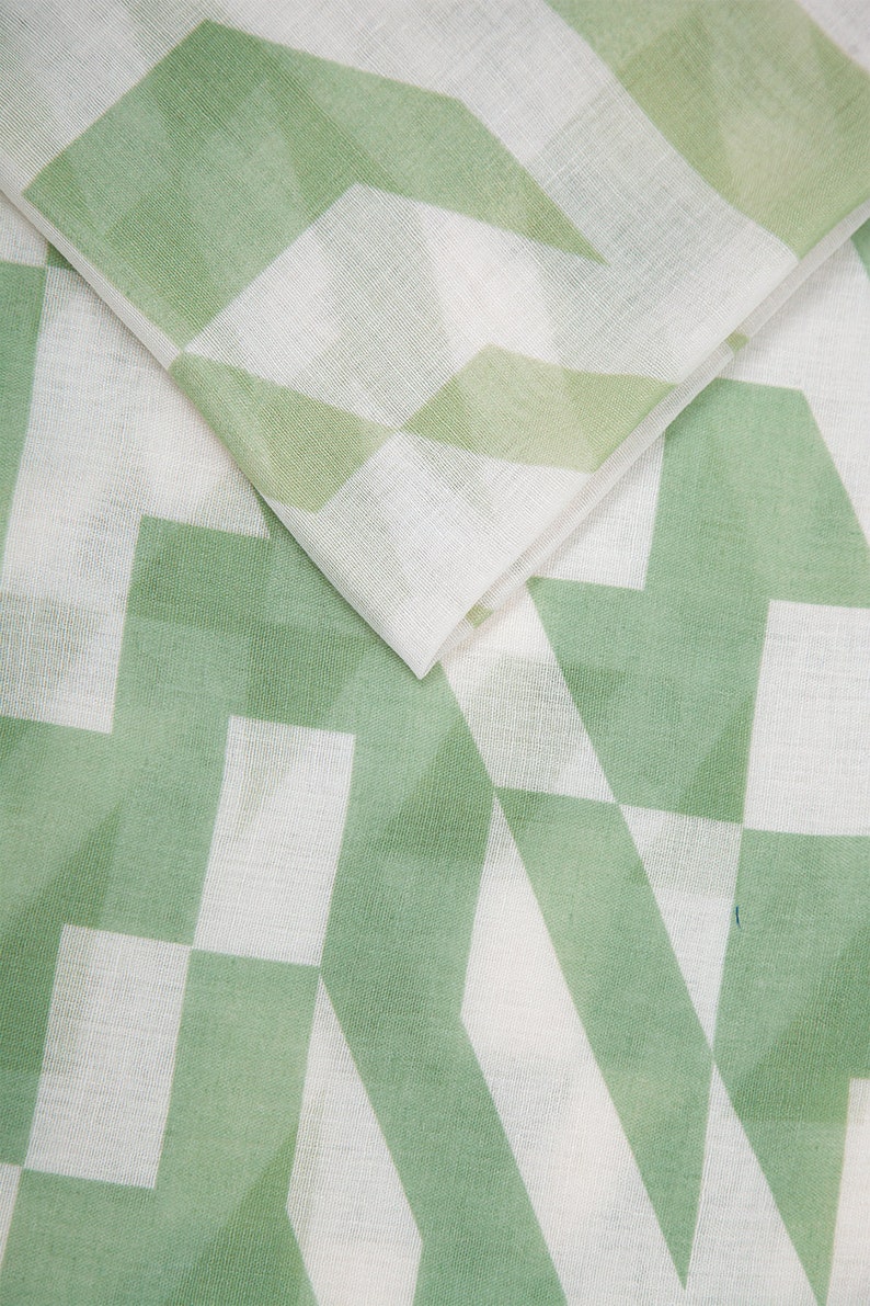 May include: White fabric with a green geometric pattern. The pattern is made up of overlapping squares and triangles.