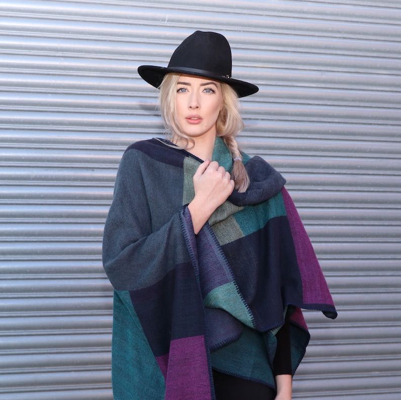model wearing the poncho as an outer layer, poncho is accessorised with a winter hat