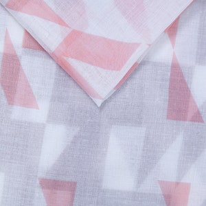 May include: White fabric with a pink geometric pattern. The fabric is folded in half, showing the pattern on both sides.