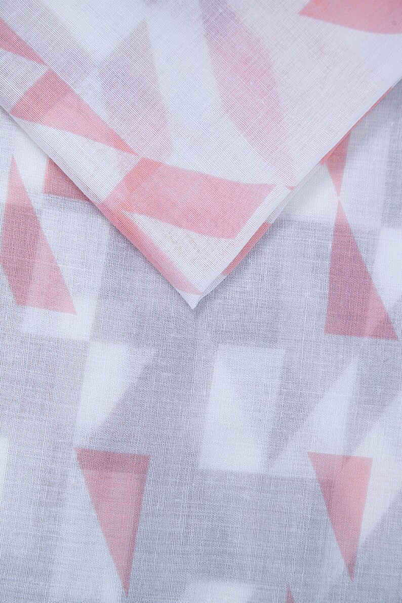 May include: White fabric with a pink geometric pattern. The fabric is folded in half, showing the pattern on both sides.