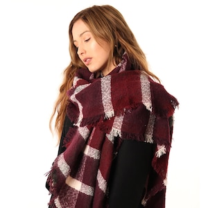 model wearing a burgundy tartan blanket scarf around her neck and shoulders