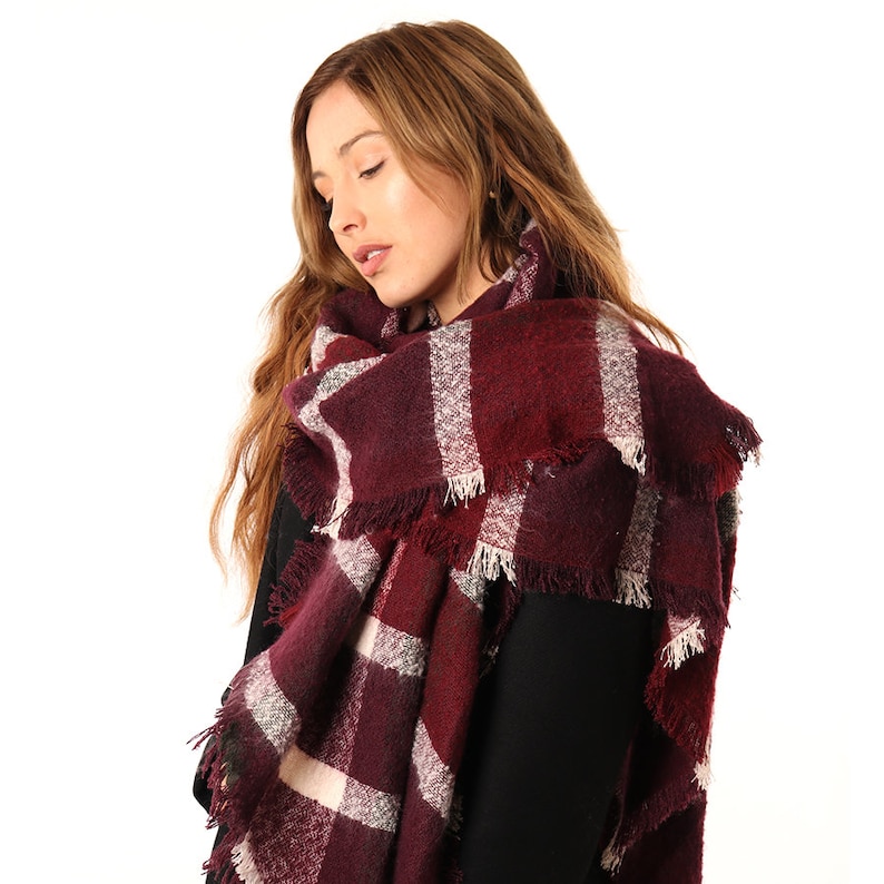 model wearing a burgundy tartan blanket scarf around her neck and shoulders