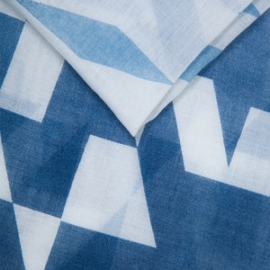 May include: A white fabric with a blue geometric pattern. The fabric is folded in half, showing the pattern on both sides.