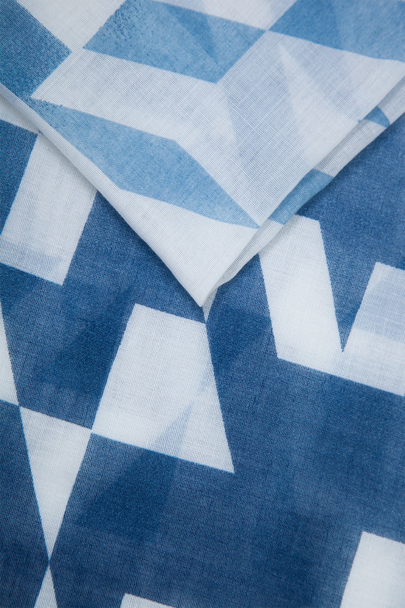 May include: A white fabric with a blue geometric pattern. The fabric is folded in half, showing the pattern on both sides.