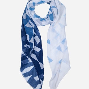 May include: A white and blue geometric patterned scarf with a fringed edge.