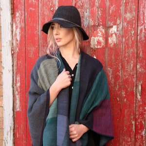 model wearing the teal patterned poncho as a layer over a shirt