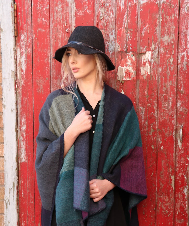 model wearing the teal patterned poncho as a layer over a shirt