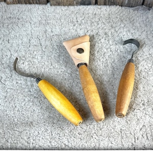 Puede incluir: Tres herramientas de talla de madera con fundas de cuero. Las herramientas tienen mangos de madera y cuchillas de metal. Las cuchillas son curvas y están diseñadas para tallar madera.  KNIVES NOT INCLUDED.