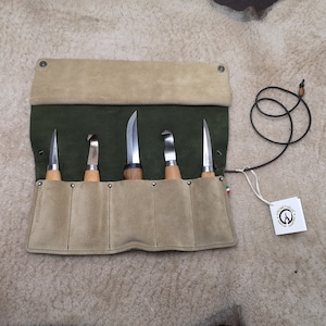 Może przedstawiać: Zestaw pięciu narzędzi do rzeźbienia w drewnie z drewnianymi uchwytami i metalowymi ostrzami, prezentowany w otwartym, oliwkowym i beżowym zamszowym etui na narzędzia. Z etui wisi etykieta z logo i napisem "Prometheus".