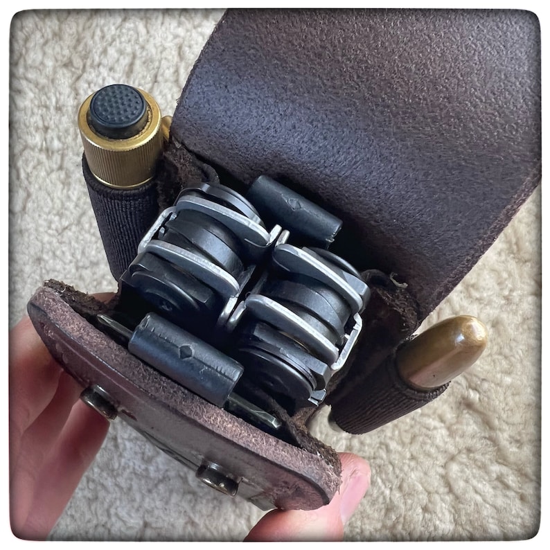 May include: A brown leather multi-tool holder with a brass-colored tool and a multi-tool with silver and black components.