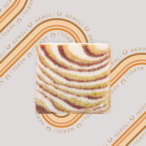 May include: A bar of soap with a swirl pattern in shades of brown and white. The soap is surrounded by a pattern of the word "NEROLI" in a circular design.