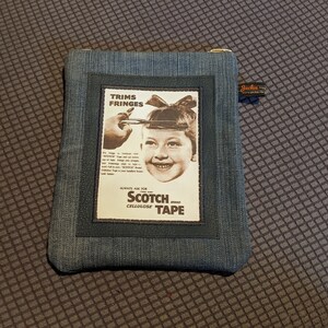 May include: A blue denim zippered pouch with a vintage Scotch Cellulose Tape advertisement featuring a young girl with a bow in her hair. The ad text reads "Trims Fringes Always Ask for Scotch Brand Cellulose Tape".