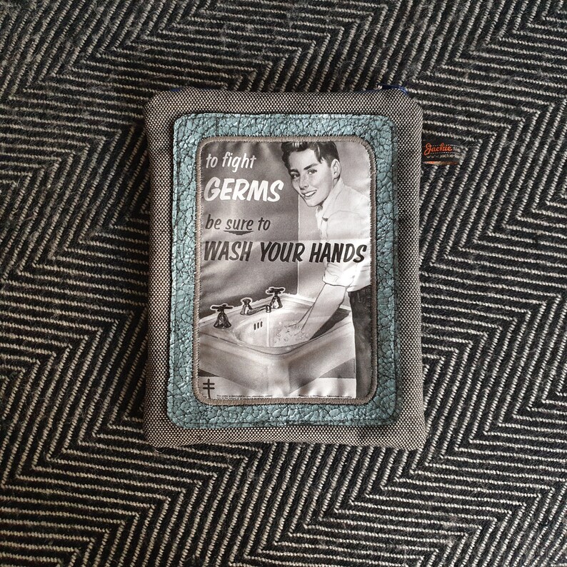 May include: A gray fabric pouch with a blue and white patch featuring a vintage illustration of a boy washing his hands at a sink. The patch has the text "to fight GERMS be sure to WASH YOUR HANDS".