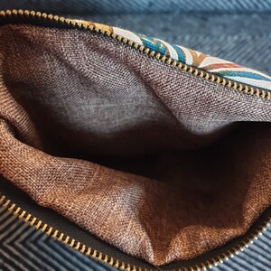 May include: The inside of a small bag or pouch with a brown fabric lining and a zipper closure.
