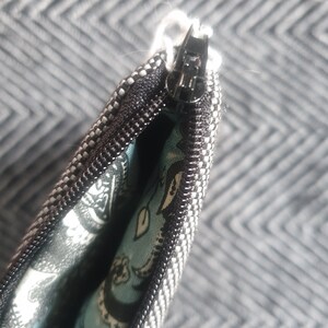 May include: Close-up of a black and white striped zipper pouch with a blue and white paisley lining. The zipper is open and the lining is visible.