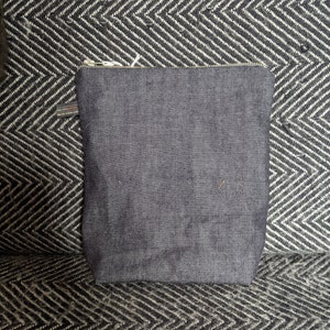 Puede incluir: Una bolsa de cremallera de mezclilla azul oscuro con un tirador de cremallera que dice "Made in USA".