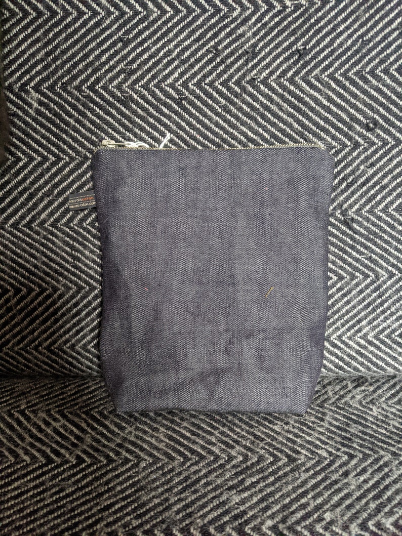 Puede incluir: Una bolsa de cremallera de mezclilla azul oscuro con un tirador de cremallera que dice "Made in USA".