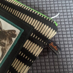 May include: Black and beige zippered pouch with a green trim and a black and white animal print. The pouch has a label that says "Jackie file" and "www.jackie-file.net".