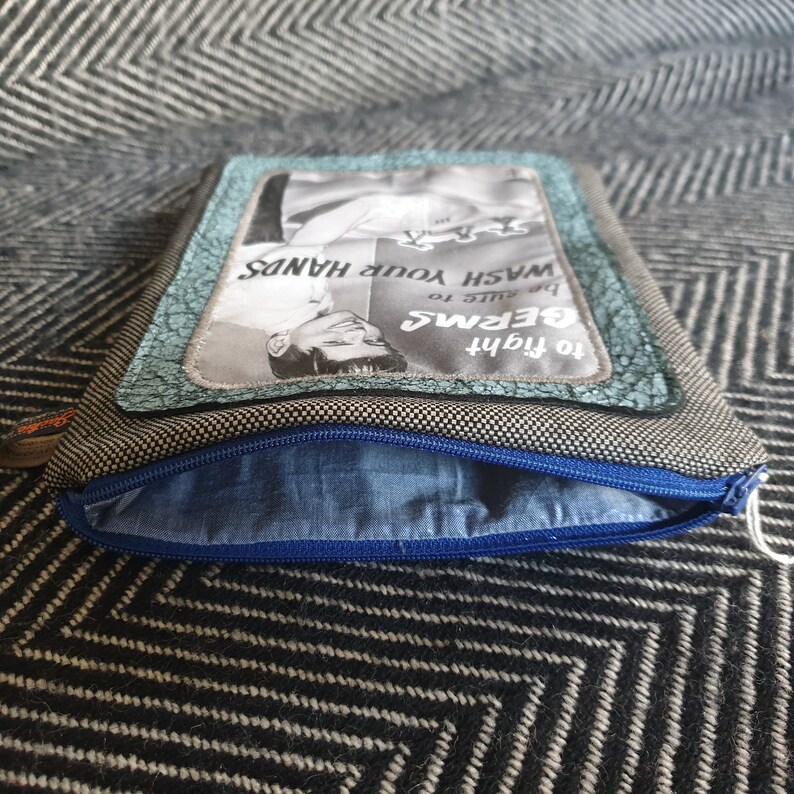 May include: A gray and black zippered pouch with a blue lining. The pouch has a vintage-style advertisement on the front that reads "To fight germs, be sure to wash your hands."