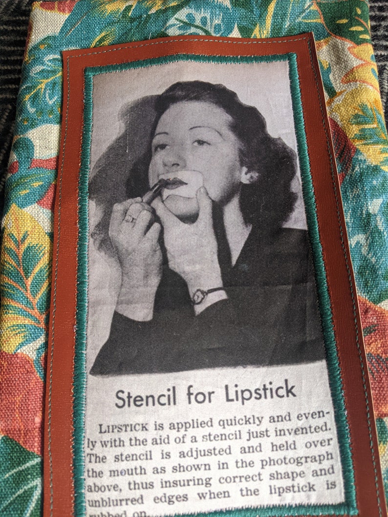 Pu&ograve; includere: Una fotografia in bianco e nero di una donna che applica il rossetto usando uno stencil. La foto &egrave; incorniciata con un bordo in pelle marrone e un bordo verde acqua. Il testo sotto la foto recita "Stencil for Lipstick" e spiega come usare lo stencil per applicare il rossetto in modo uniforme.