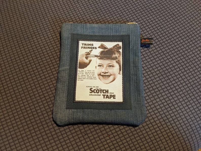 May include: A blue denim zippered pouch with a vintage Scotch Cellulose Tape advertisement featuring a young girl with a bow in her hair. The ad text reads "Trims Fringes Always Ask for Scotch Brand Cellulose Tape".