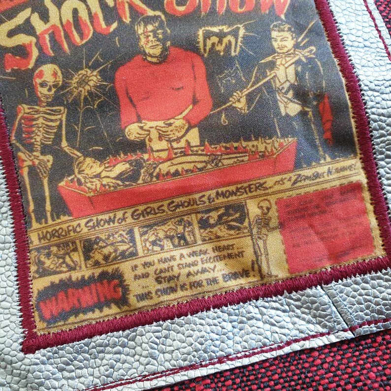 Op de afbeelding: Een vintage-stijl poster die reclame maakt voor een "Horrific Show of Girls, Ghouls & Monsters." De poster toont een skelet, een monster en een goochelaar voor een brandende kist. De tekst "WAARSCHUWING" wordt in rood weergegeven met de boodschap "Als je een zwak hart hebt en geen opwinding kunt verdragen, blijf weg. Deze show is voor de dapperen!"