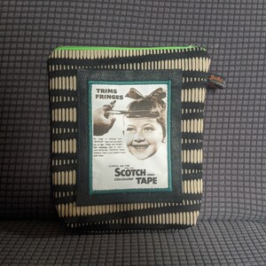 May include: A black and white zippered pouch with a green zipper pull. The pouch has a vintage advertisement for Scotch Cellulose Tape featuring a young girl with a bow in her hair. The ad text reads "Trims Fringes", "Scotch", and "Cellulose Tape".