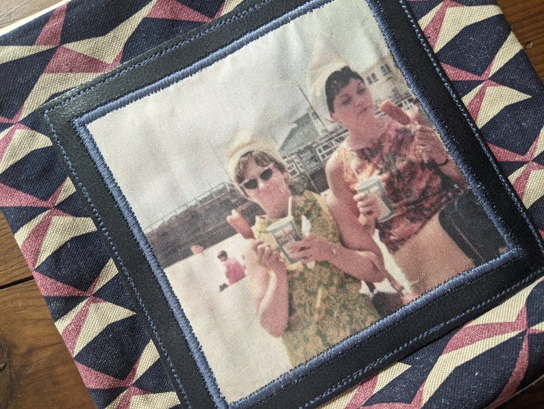 以下が含まれることがあります： ビーチでアイスクリームコーンを楽しむ2人の女性のヴィンテージ写真。女性はサマードレスとサングラスを着用しています。写真は黒と青の縁取りで額装され、幾何学模様のファブリックの背景にマウントされています。
