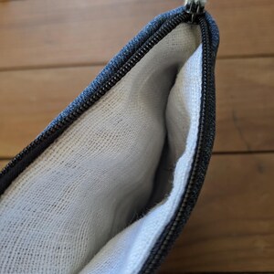 May include: A black zippered pouch with a white cotton lining. The pouch is open and the lining is visible.