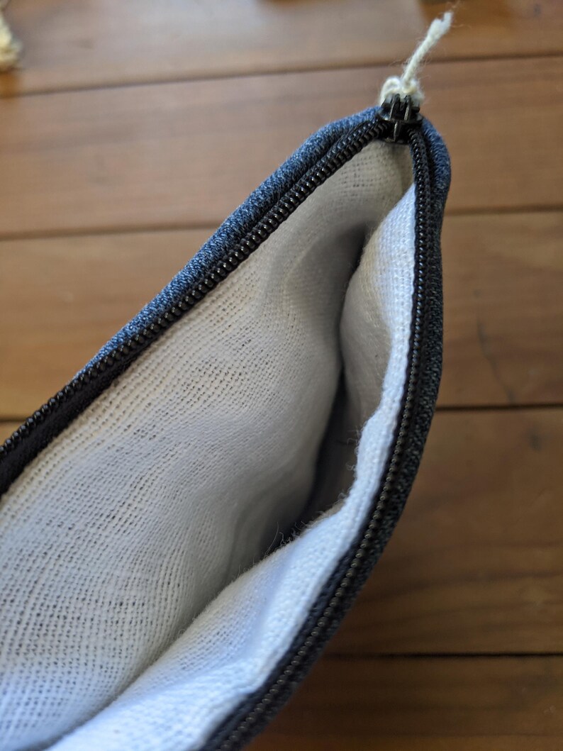 May include: A black zippered pouch with a white cotton lining. The pouch is open and the lining is visible.