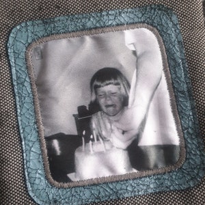 May include: A black and white photo of a young girl crying while blowing out candles on a birthday cake. The photo is framed in a blue and gray border.