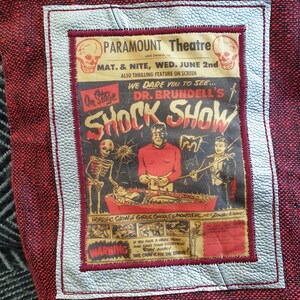 Op de afbeelding: Een vintage poster die reclame maakt voor een horror show genaamd "Dr. Brundell's Shock Show" in het Paramount Theatre. De poster toont een skelet, een monster en een man in smoking. De tekst op de poster luidt "We durven je uit te dagen om te zien... Dr. Brundell's Shock Show. Gruwelijke show met meisjes, geesten en monsters."