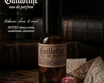 May include: A brown glass spray bottle of Guillotine eau de parfum with a black cap and a tan label featuring the text Guillotine, eau de parfum, tobacco, lace & oud, and a list of notes including tobacco, tonka, sandalwood, and clementine.