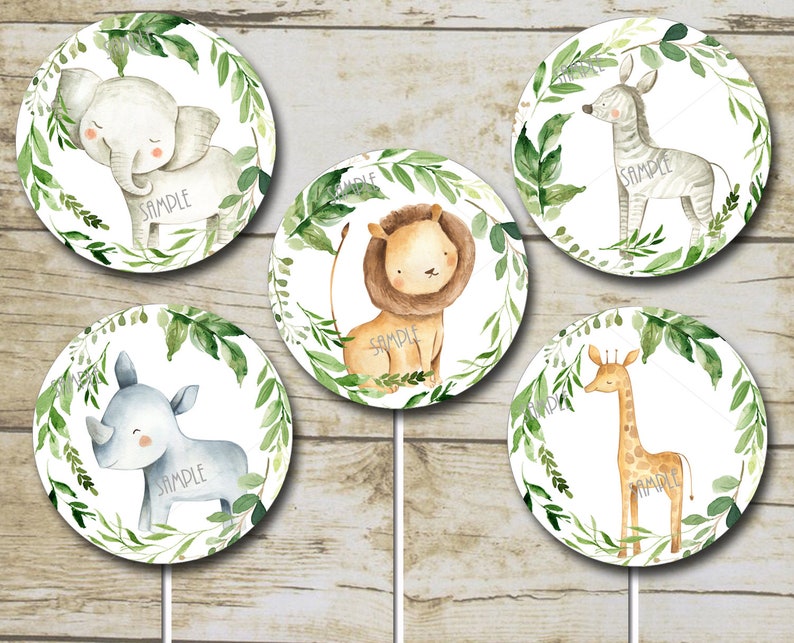 May include: Five round cake toppers with watercolor illustrations of jungle animals. The animals are a giraffe, zebra, rhino, lion, and elephant. Each animal is surrounded by green leaves and a white background.