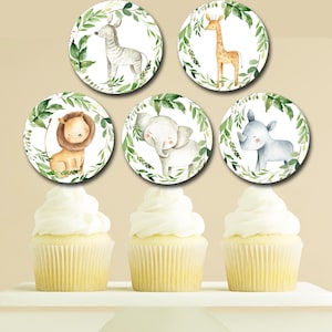 May include: Six cupcake toppers featuring jungle animals. Each topper is a circle with a white background and a green leafy border. The animals include a lion, elephant, rhinoceros, giraffe, and zebra.