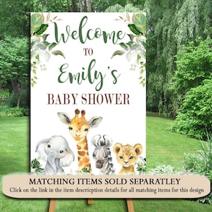 May include: Welcome to Emily's Baby Shower sign with a white background and green foliage. The sign features a giraffe, zebra, and lion with a brown text box that says "Matching Items Sold Separately".