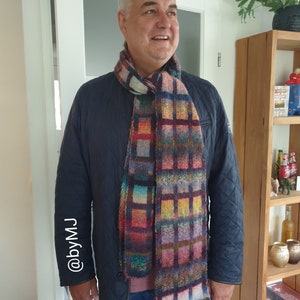 May include: A man wearing a black quilted jacket with a colourful plaid scarf. The scarf has a variety of colours including red, blue, green, yellow, and brown. The man is smiling and looking to the right.