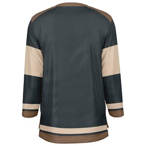 May include: A dark blue hockey jersey with white and brown stripes on the sleeves and bottom. The jersey has a brown collar.