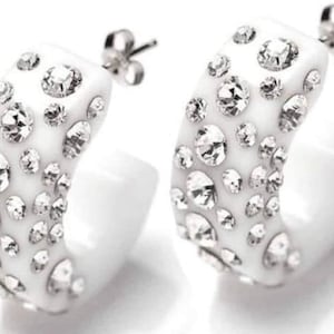 May include: White hoop earrings with a silver post and a white base covered in clear rhinestones.