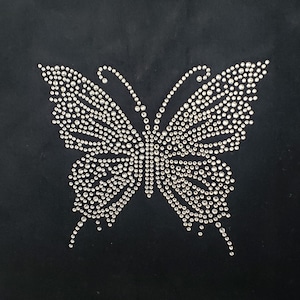 May include: A black fabric background with a silver rhinestone butterfly design.