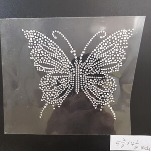 May include: A clear sheet with a silver butterfly design made of rhinestones. The butterfly is 5 1/2 inches by 4 1/8 inches.