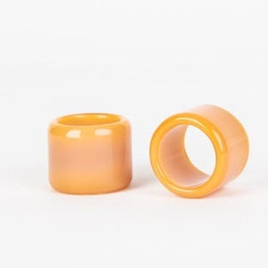 May include: Two orange and white striped napkin rings made of ceramic.